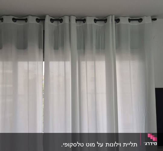 וילונות לבנים תלויים על מוט מתכת שחור